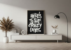 Modern living room with a black framed poster on a white wall, plants, and a lamp.