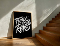 Framed poster with 'Fuck the Rules' text on a wall next to wooden stairs