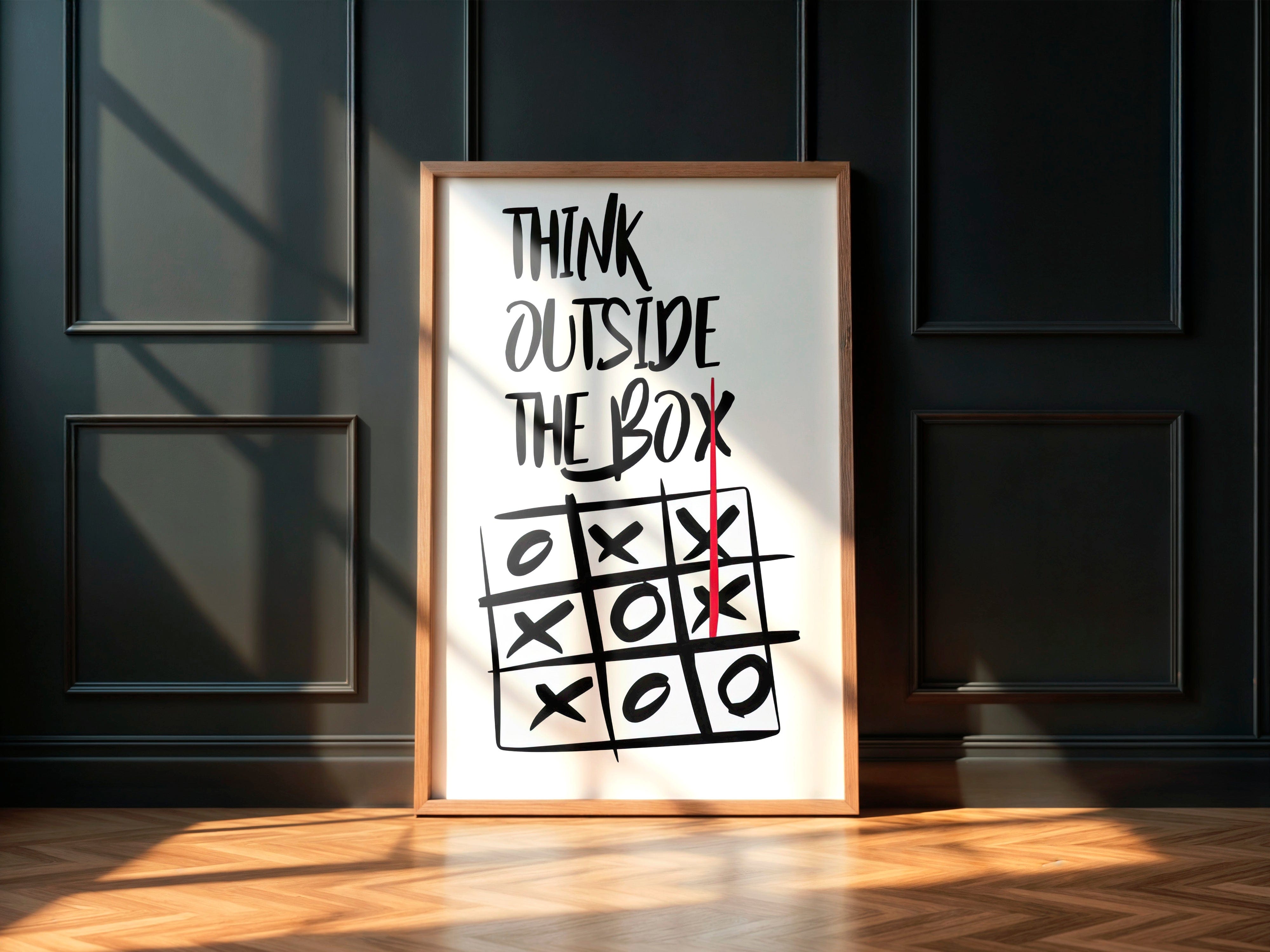 Framed poster with 'Think Outside The Box' quote and tic-tac-toe game on a dark wall.