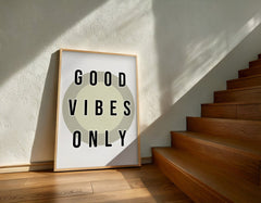 Framed 'Good Vibes Only' poster on a wall next to wooden stairs