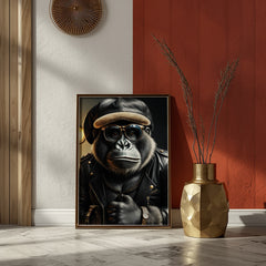 Framed artwork of a gorilla wearing a leather jacket and hat in a room with a red wall and gold vase.