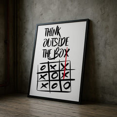 Framed poster with 'Think Outside The Box' quote and tic-tac-toe game on a concrete wall.