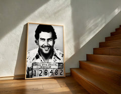 Framed black and white portrait of a man with a smile on a wall next to wooden stairs.