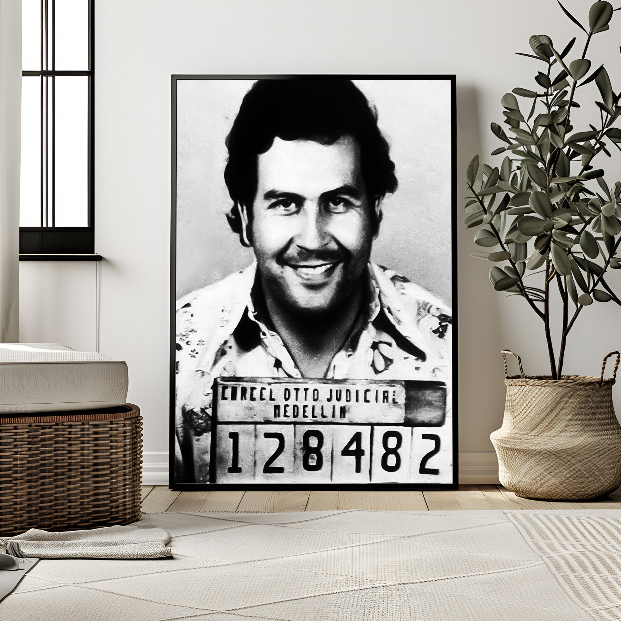 Framed black and white portrait of a man with a mugshot-style label in a room with decor elements.