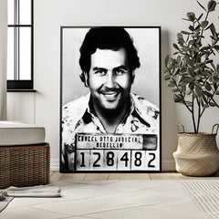 Framed black and white portrait of a man with a mugshot-style label in a room with decor elements.