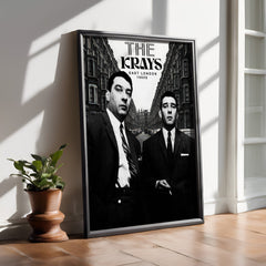 Framed poster of 'The Krays' on a wall with a plant on a wooden floor.