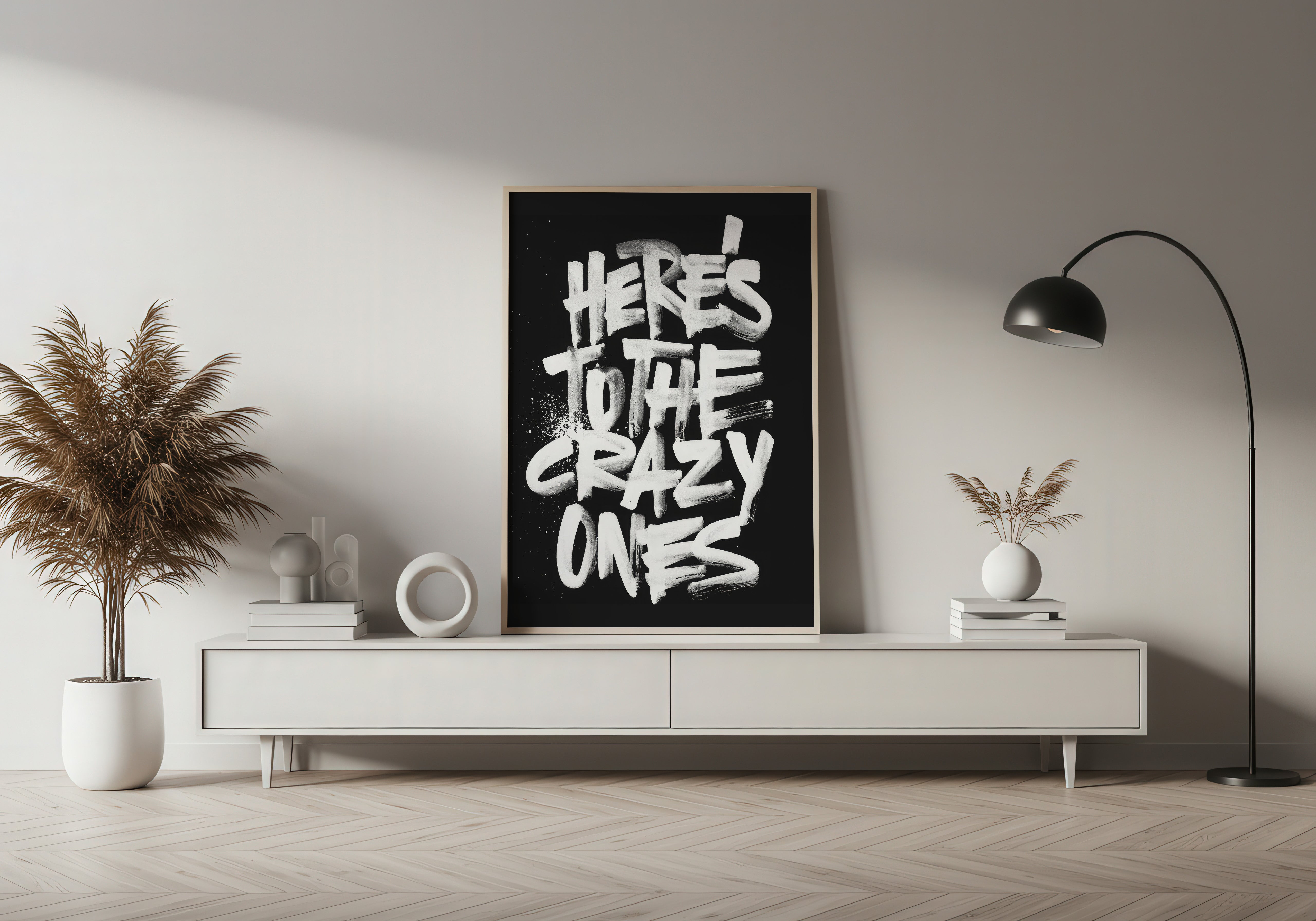 Modern living room with a black framed poster on a white wall, plants, and a lamp.