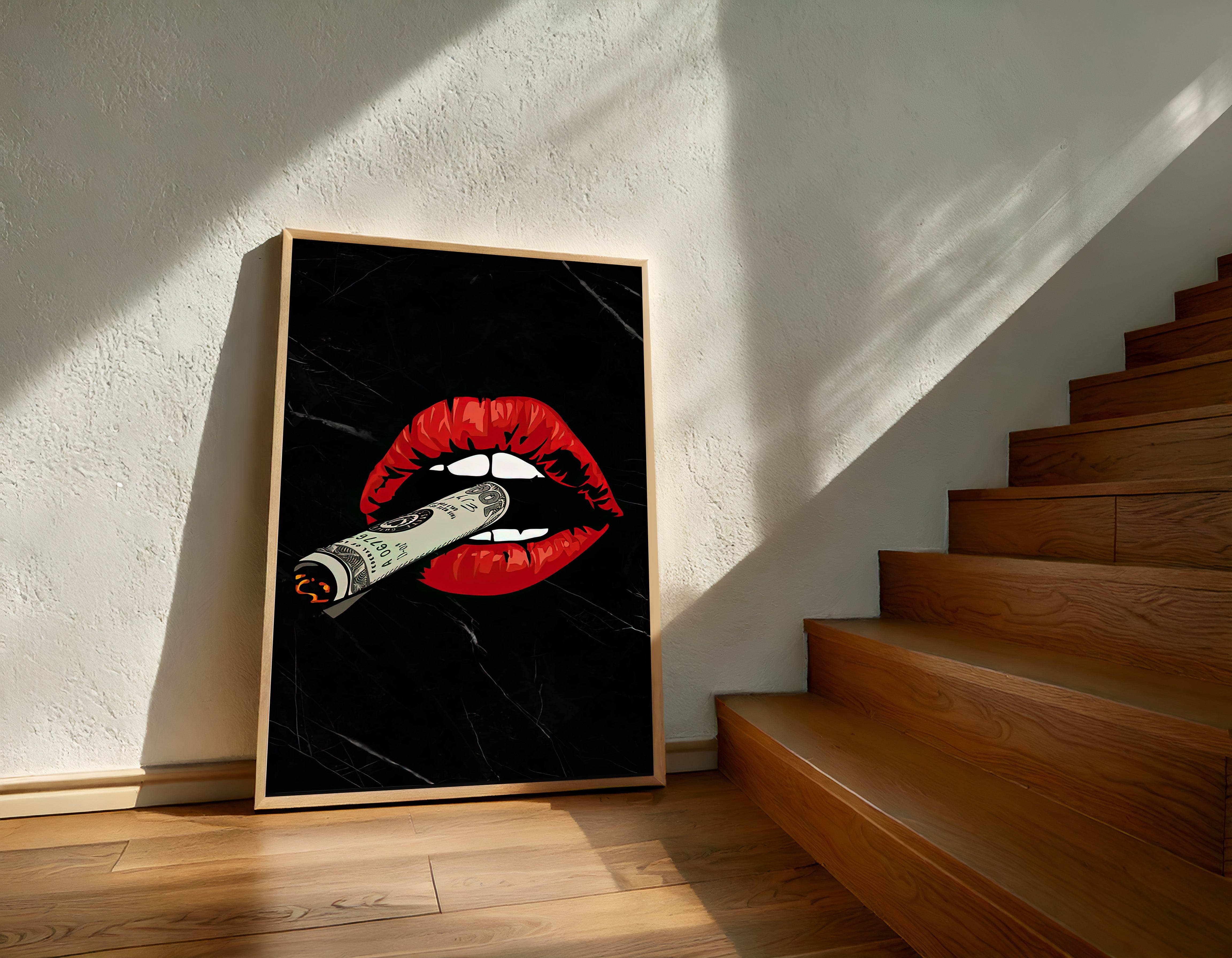 Framed artwork of red lips with a cigarette on a black background, leaning against a wall next to wooden stairs.