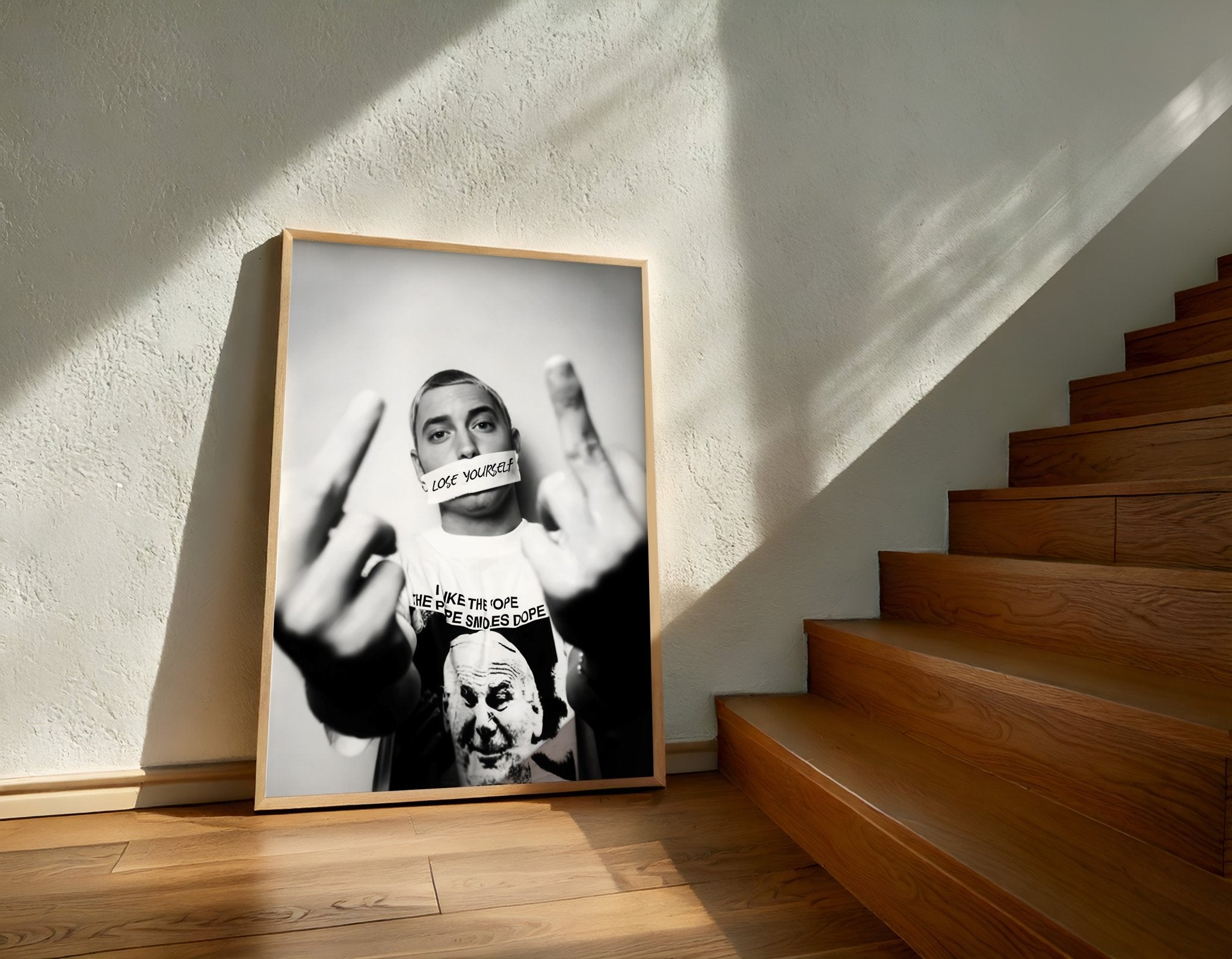 Framed black and white artwork on a wall with wooden stairs in the background