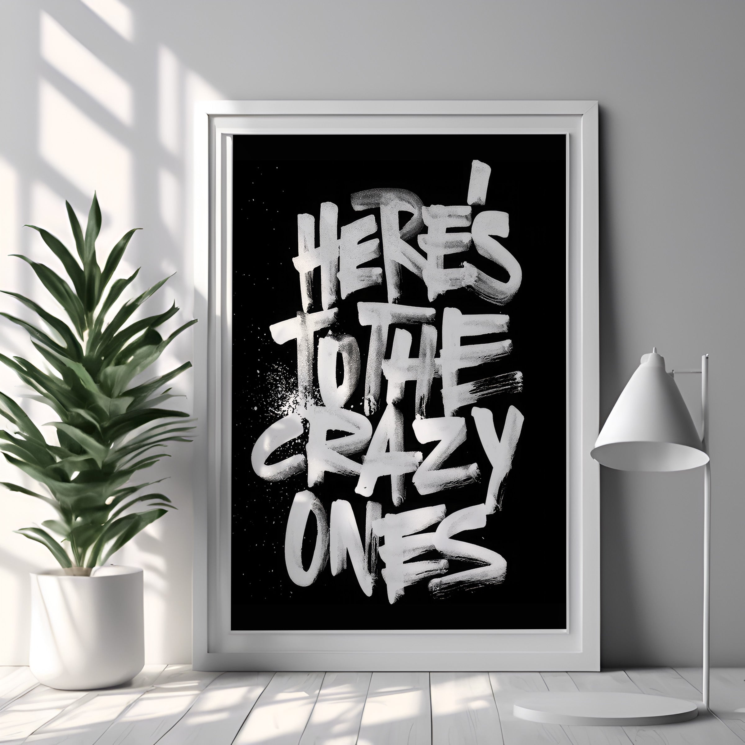 Framed poster with 'Here's to the crazy ones' text in a modern interior setting.