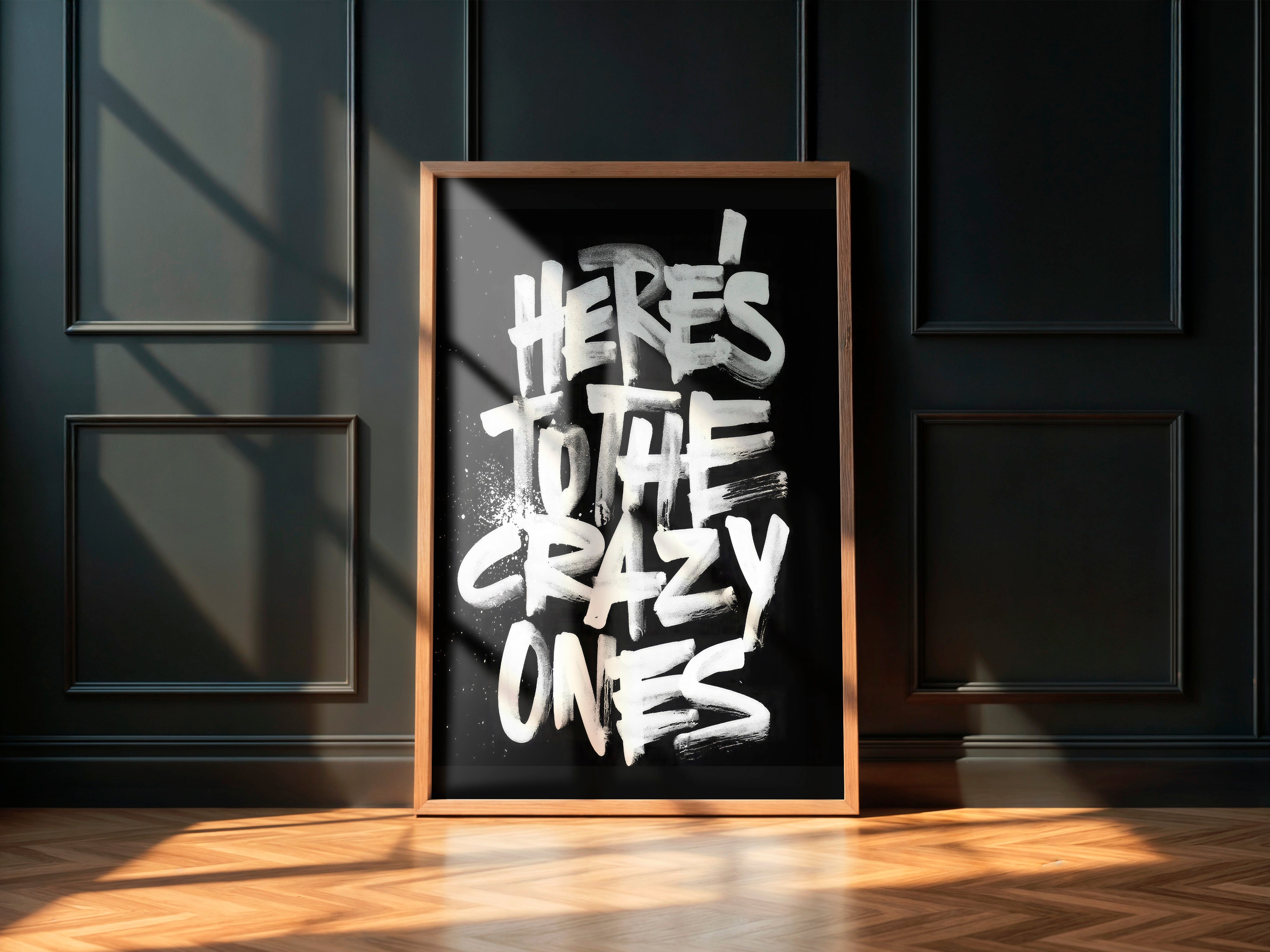 Framed artwork with 'Here's to the crazy ones' text on a dark wall.
