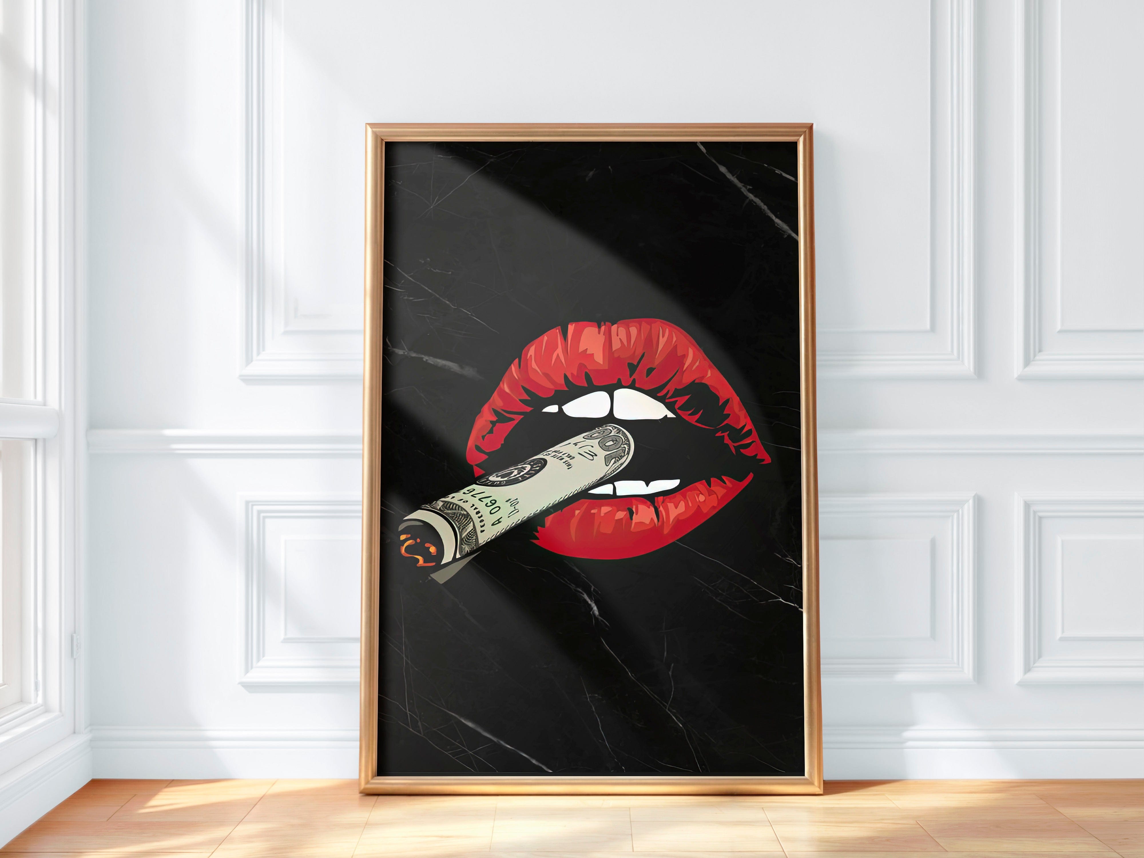 Framed artwork of red lips with a dollar bill inside on a black background, displayed on a white wall.